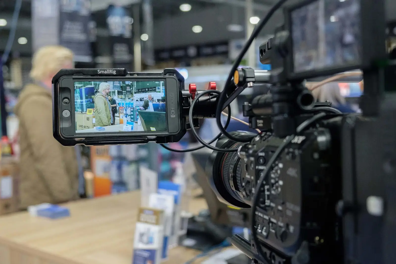 A professional video camera recording a man and woman shopping in a store aisle.